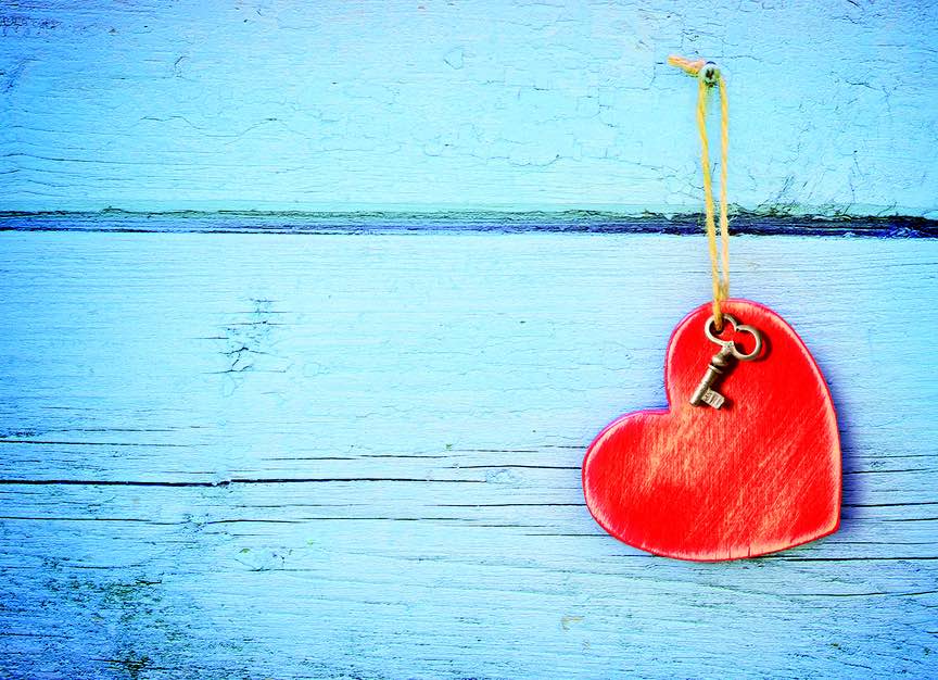 Bronze key and red wooden heart hanging on antique teal blue old wood door. Valentines Day. Holiday concept.